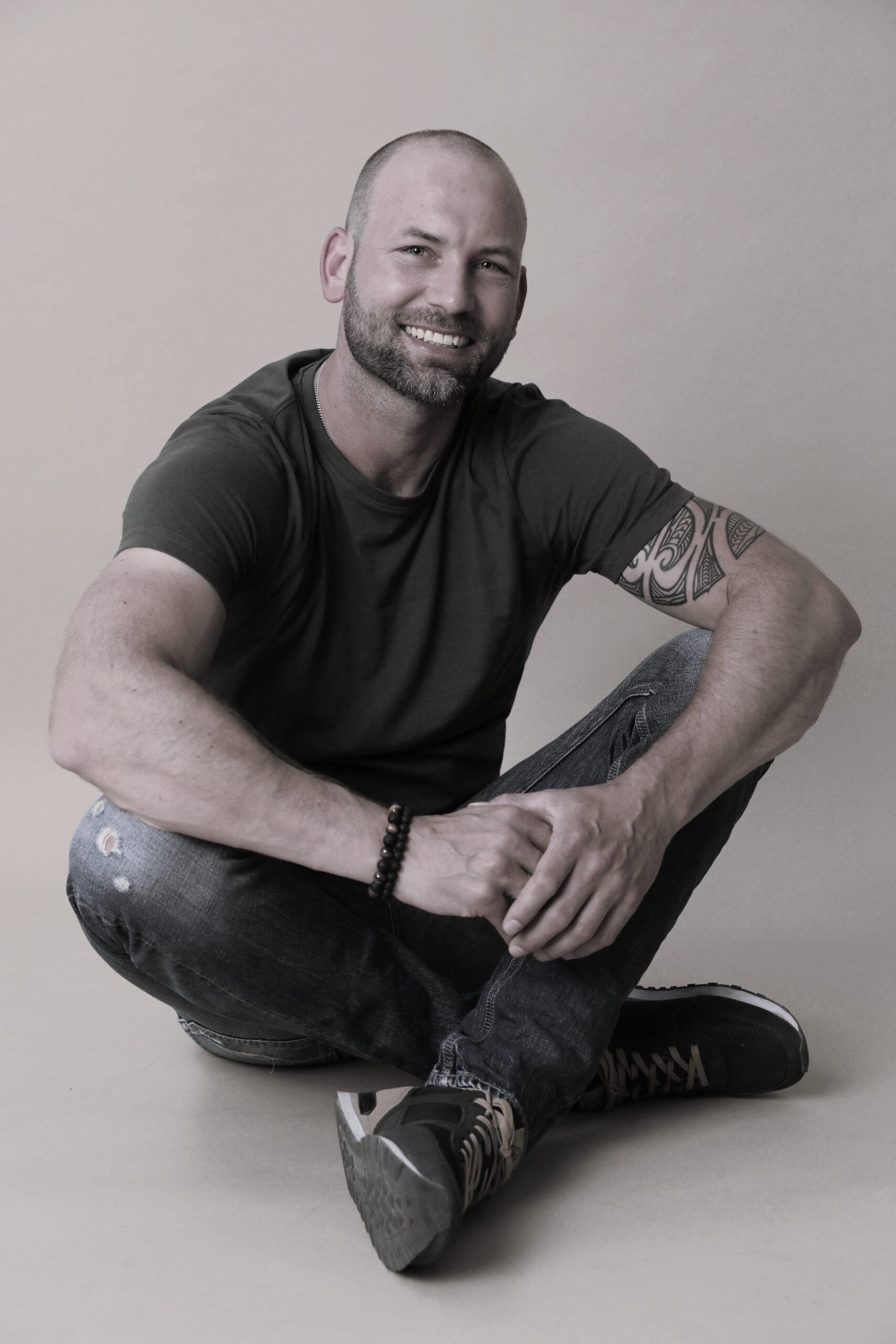 Ein Bild vom DT Copywriter, er sitzt auf einem Stuhl, lehnt sich zurück und trägt einen Anzug. Lächelt in die Kamera und sieht entspannt aus.